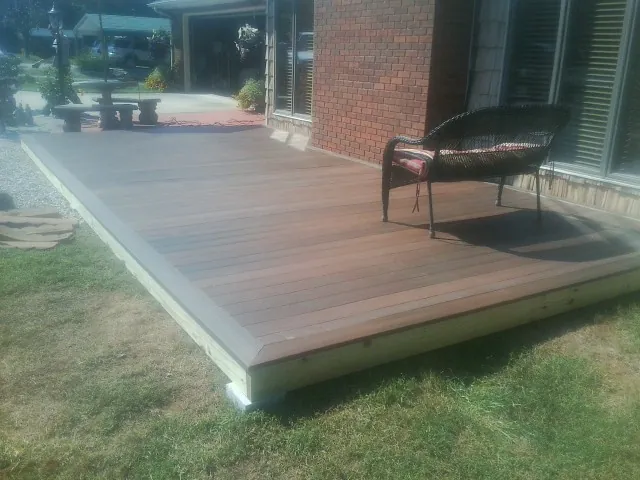 New wood deck and wicker chair beside a brick house in Chesterfield